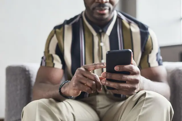 A man in a striped shirt using his phone